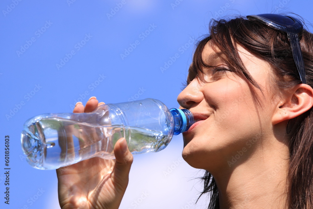 Girl drinking water against blue sky in sunny day Girl drinking water against blue sky in sunny day