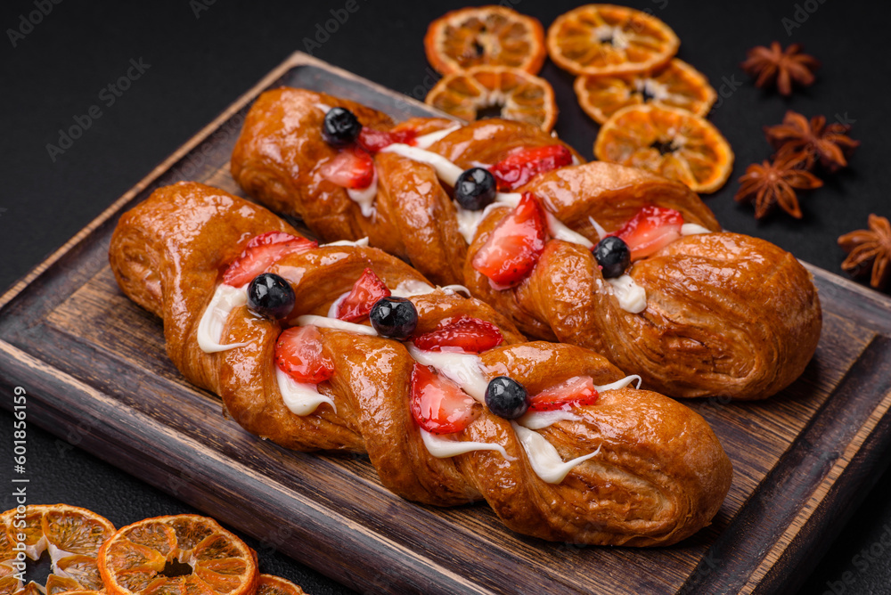Delicious fresh crispy pastry in the form of a pigtail with strawberries and blueberries Delicious fresh crispy pastry in the form of a pigtail with strawberries and blueberries