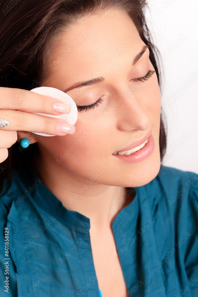 Young woman removing makeup with cleansing pad