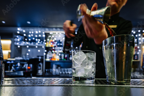 man bartender hand making negroni cocktail. Negroni classic cocktail and gin short drink with sweet vermouth, red bitter liqueur