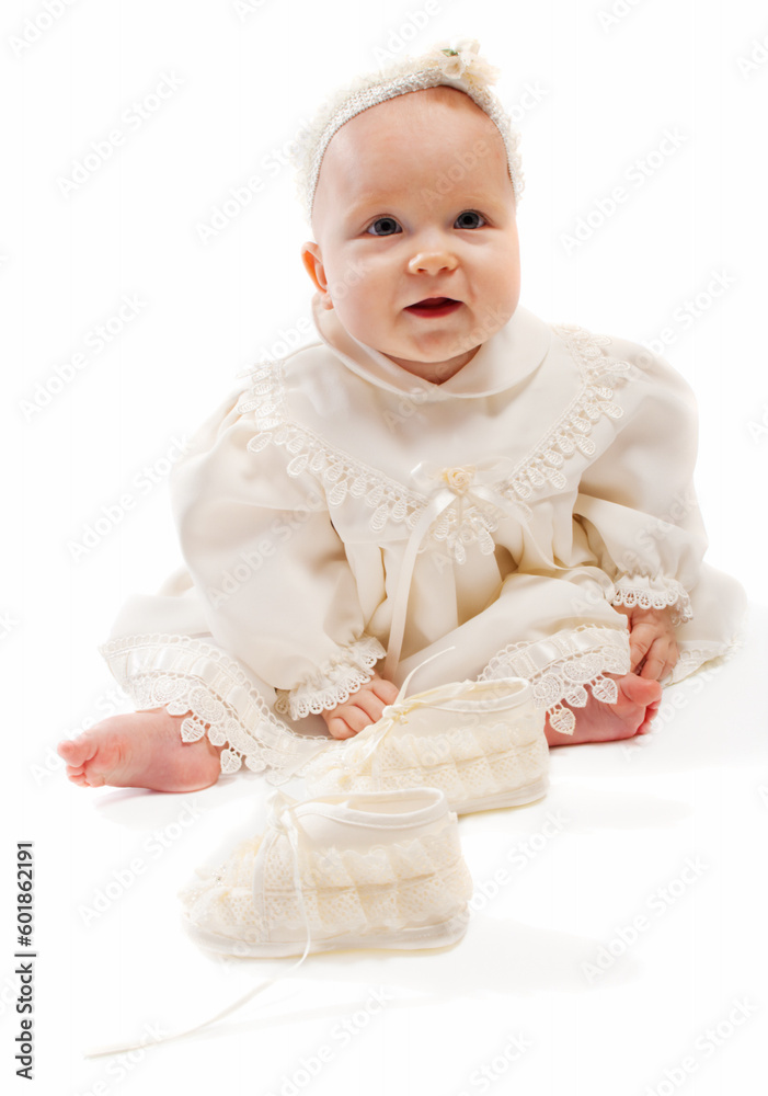 Baby in milky baptismal clothes sitting beside bootees Baby in milky baptismal clothes sitting beside bootees