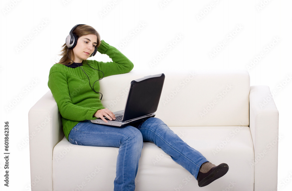 Young woman with headphones and a laptop, seated on a sofa isolated on white Young woman with headphones and a laptop, seated on a sofa isolated on white