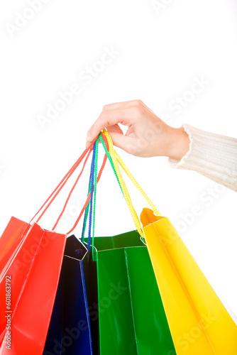 Woman hand holds coloured shopping bags. Isolated on white.