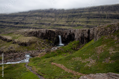 Fototapeta Naklejka Na Ścianę i Meble -  Scenic view of the waterfall flowing between green cliffs in Iceland