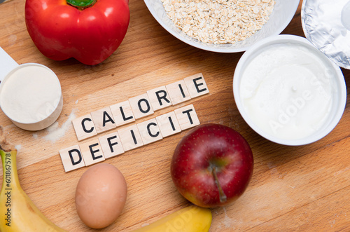 Foto Inscription calorie deficit next to fruit, eggs, protein powder and oatmeal