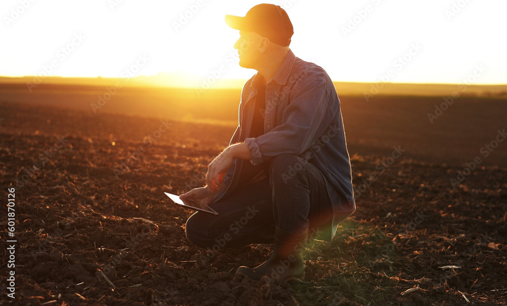 Φωτογραφία Agronomist touches soil examine and testing cultivated land before sowing on agricultural field and typing results in digital tablet on sunset