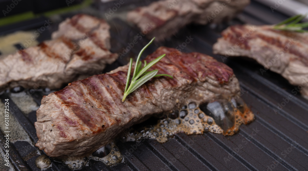 meat beef steak on electric grill cooked, with fresh rosemary. The meat is roasted with stripes. hot photo with steam. grill season
