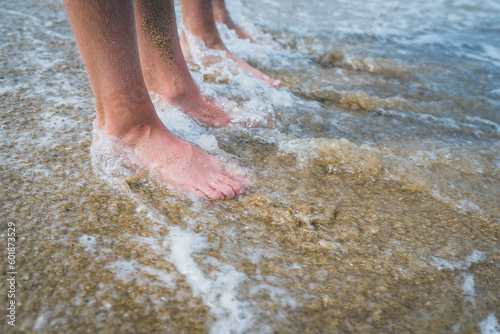 Two pairs of kids feet on the sand in the water .Family on vacations. Feet and the grains of sand. 