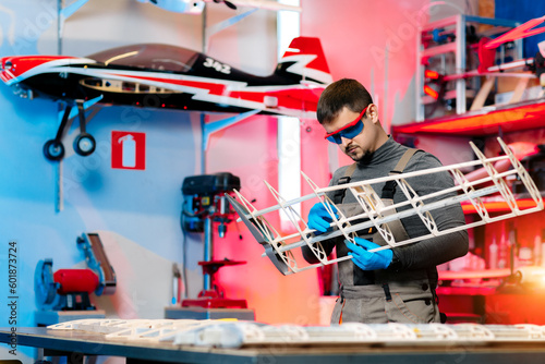 Young male engineer or technician working on drone details in lab. Aircraft capable of GPS surveillance. Carbon. photo