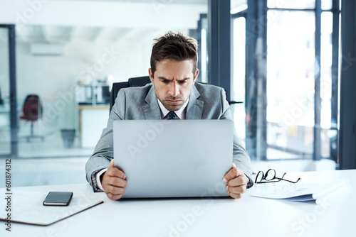 Stress, frown and angry man on laptop in office frustrated with glitch, mistake or crisis. Anxiety, face and business person with failure or problem, 404 or bad review, deadline report or tech delay photo