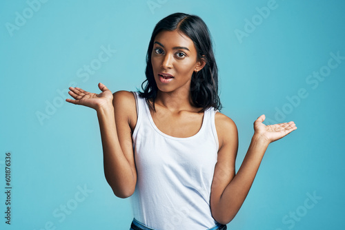 Options, choice gesture and portrait of woman in studio with shock, surprise or thinking face. Decision, idea and Indian female model with comparison or shrug hand sign by blue background with mockup