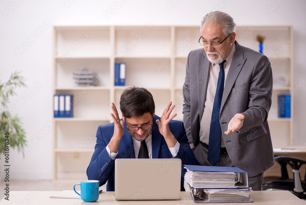 Old male boss and young male employee in the office Old male boss and young male employee in the office
