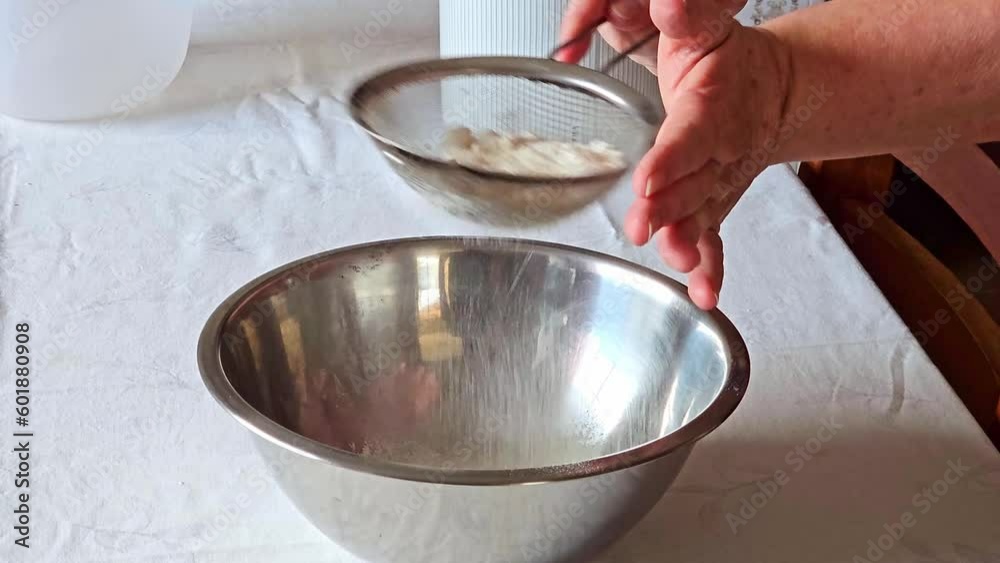 Sifting wheat into a bowl on a table in the kitchen for making a cake, 4k, selective focus. Sifting wheat into a bowl on a table in the kitchen for making a cake, 4k, selective focus.