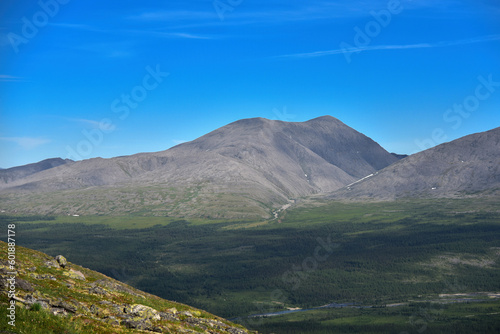 View from the mountain peak to the valley in the mountains. Blue sky. © lacemika