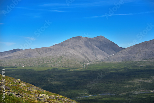 View from the mountain peak to the valley in the mountains. Blue sky.