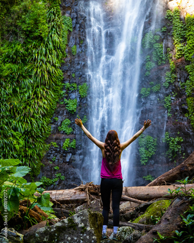 long haired hiker girl standing in frong of large tropical waterfall in lamington rainforest  queensland  australia  famous larapinta falls hidden deep in the jungle