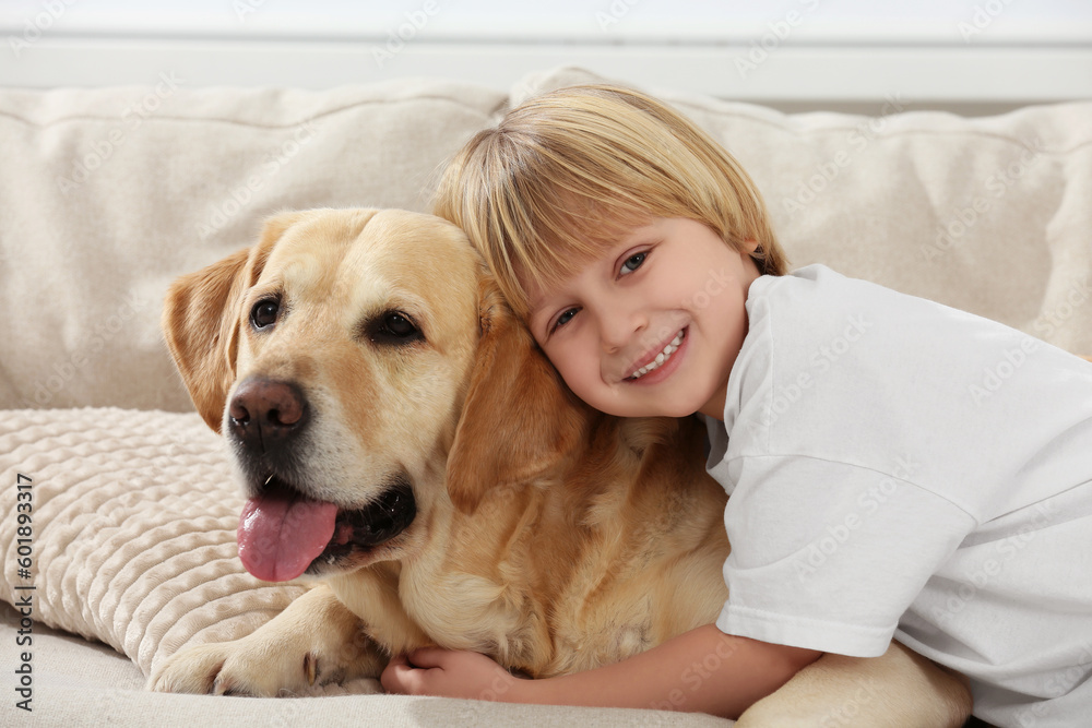 Cute little child with Golden Retriever on sofa at home. Adorable pet Cute little child with Golden Retriever on sofa at home. Adorable pet