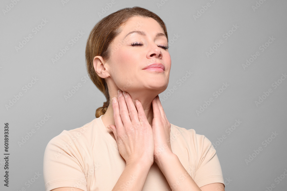 Woman suffering from sore throat on light grey background Woman suffering from sore throat on light grey background