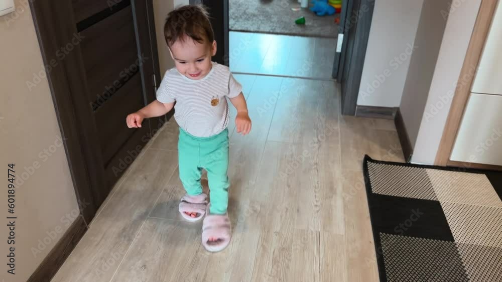 Happy baby boy put on mom’s slippers and walks in them by the room. Adorable child plays at home. Top view. Happy baby boy put on mom’s slippers and walks in them by the room. Adorable child plays at home. Top view.