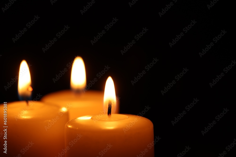 Burning wax candles on black background, closeup. Space for text Burning wax candles on black background, closeup. Space for text