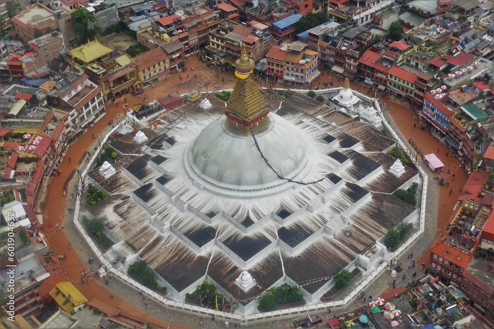 An aerial view of the Bouddhanath Stupa and its vibrant surrounding neighborhood in Kathmandu, featuring the iconic shape of a Mandala, symbolizing the universe in Buddhism. 