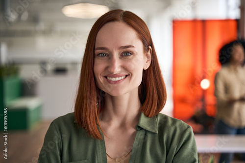 Closeup portrait of confident smiling red haired businesswoman, successful CEO looking at camera in modern office. Happy student standing in university campus, education