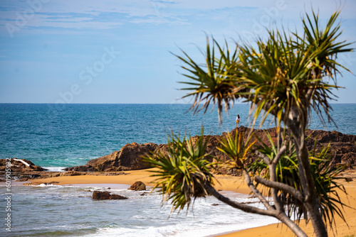 little silhouette of long haired girl standing on the rocks and gazing at the sea at wreck rock beach in deepwater national park near agnes water, queensland, australia