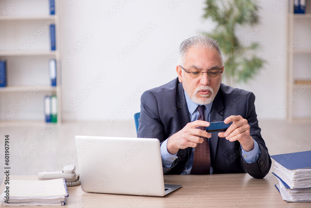 Old male employee holding credit card