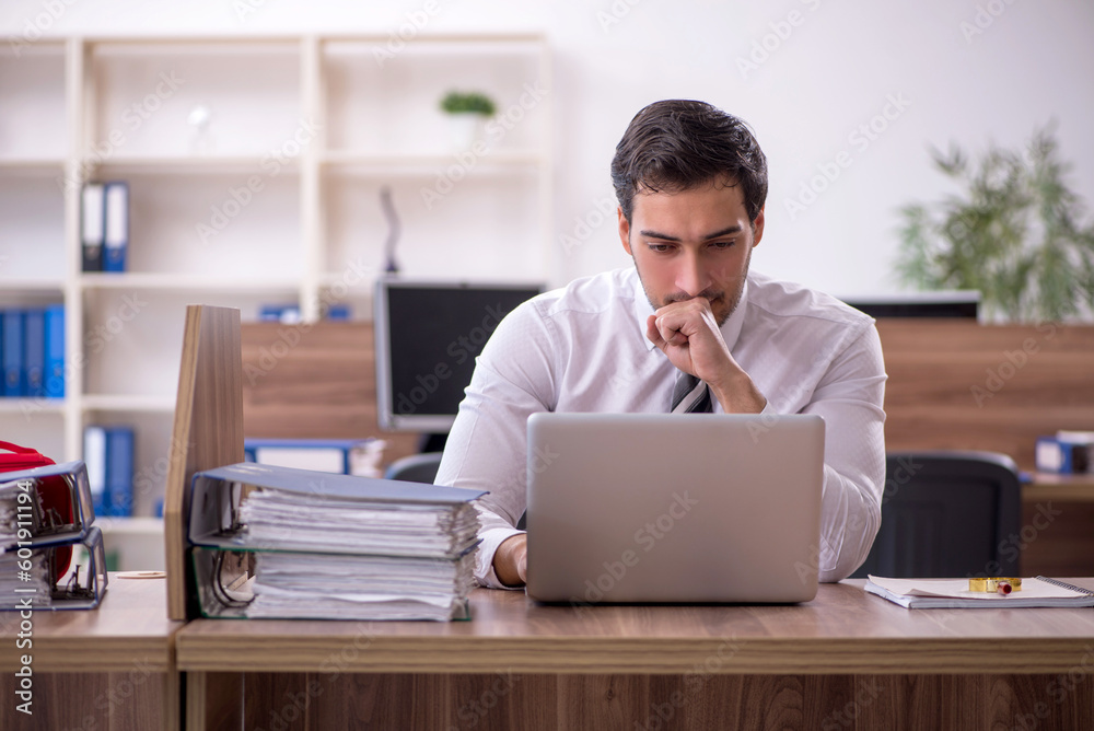 Young male employee unhappy with excessive work at workplace - obrazy, fototapety, plakaty 