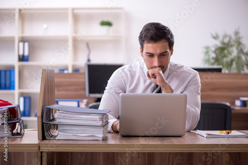 Fotografering Young male employee unhappy with excessive work at workplace