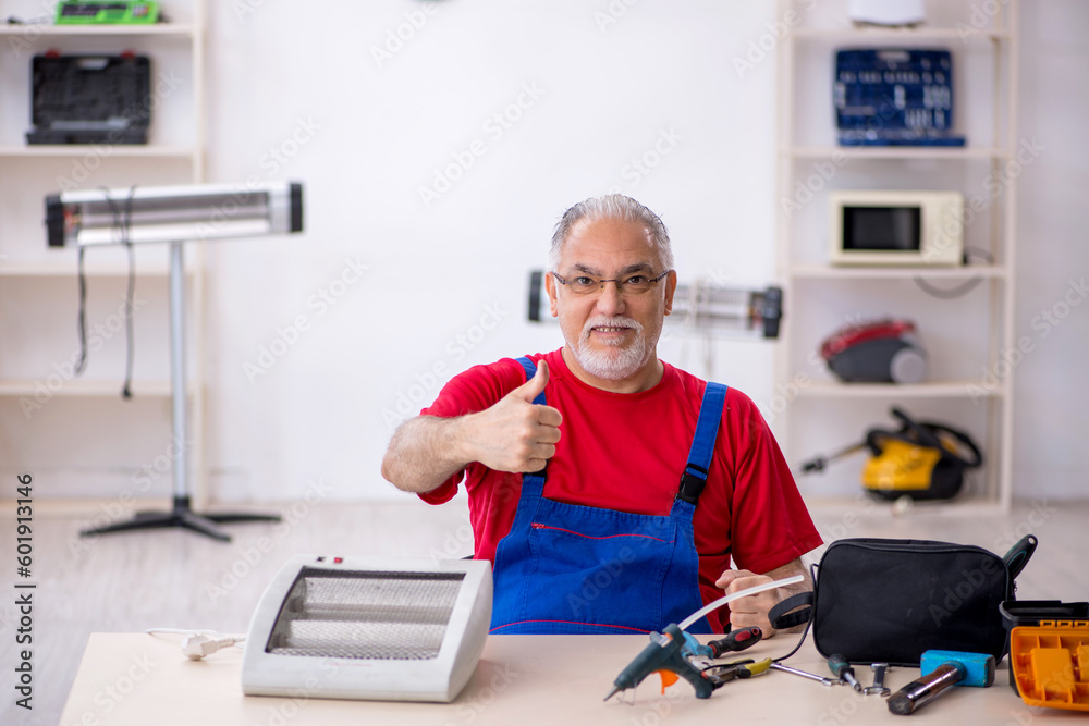 Old repairman repairing heater at workshop Old repairman repairing heater at workshop