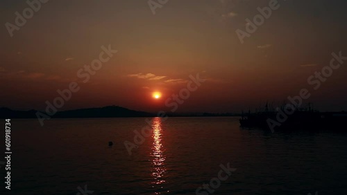 Dreamy and hypnotic ambient motion of the gentle waves reflecting the summer sunset in Koh Sdach island fishing port in Cambodia photo