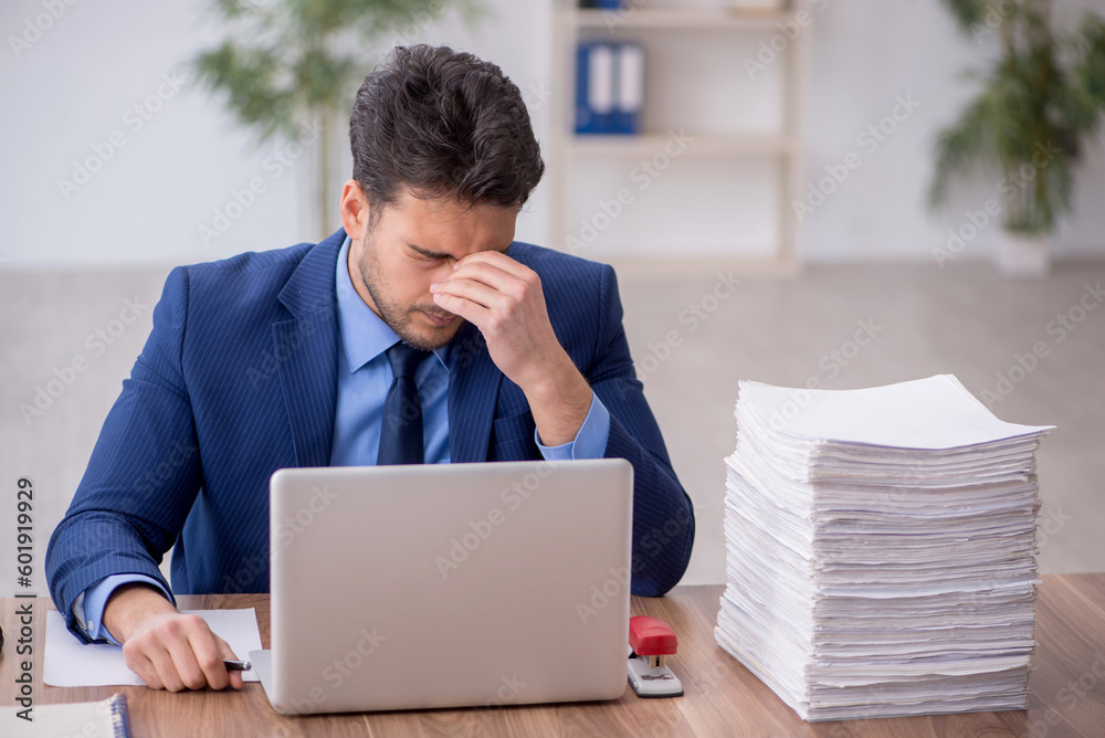 Young male employee and too much work in the office Young male employee and too much work in the office