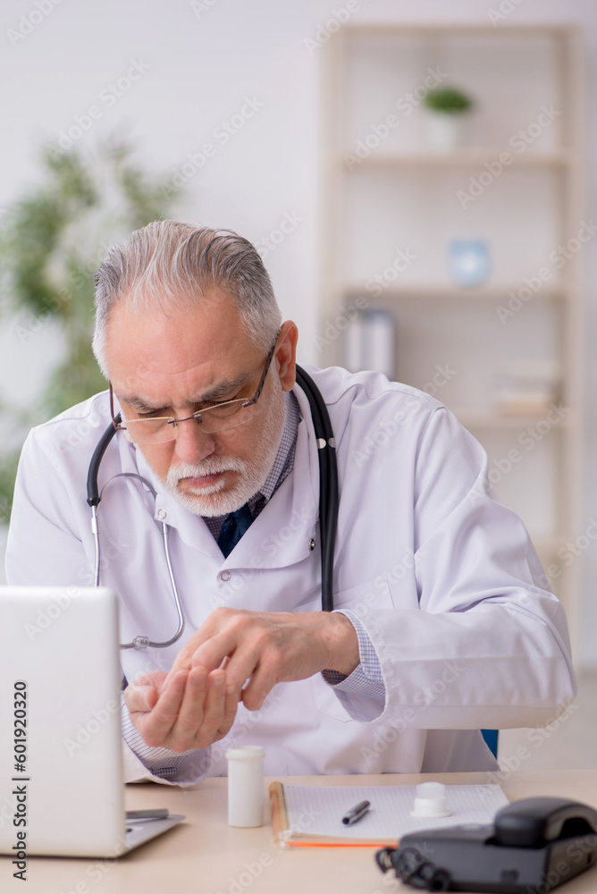 Old male doctor suggesting pills in the clinic Old male doctor suggesting pills in the clinic