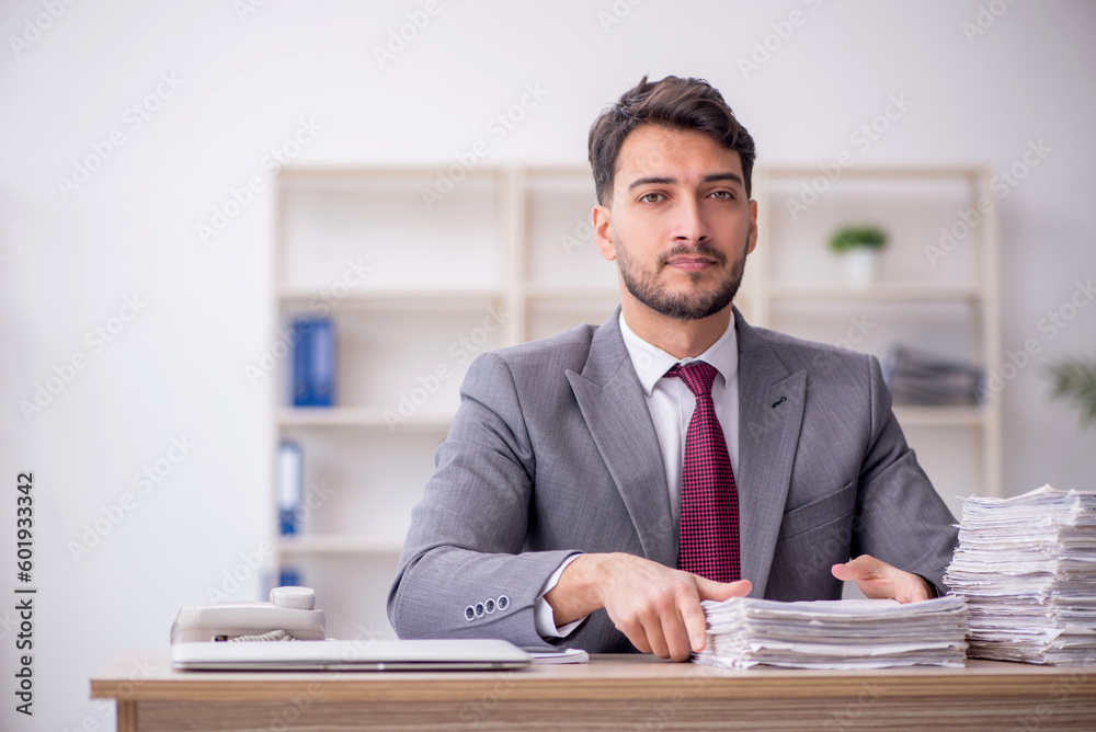 Young male employee and too much work in the office Young male employee and too much work in the office
