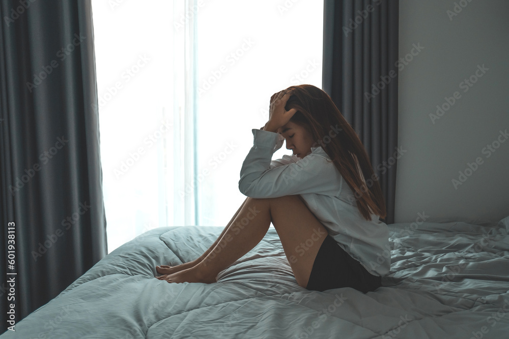 Obraz premium Depressed woman sitting head in hands in the bedroom with low light environment dramatic concept
