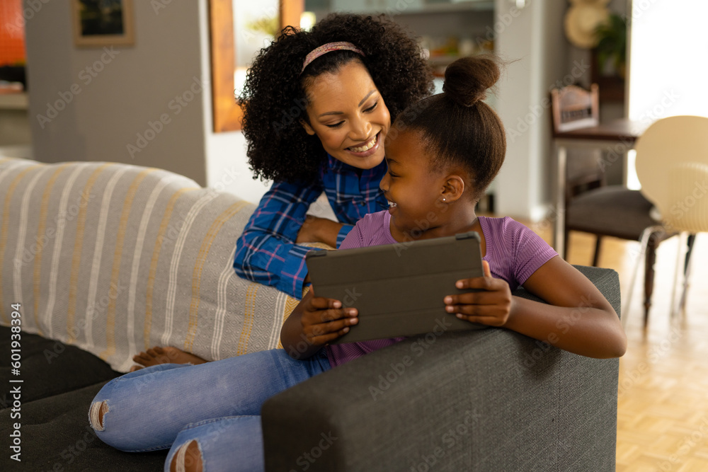 Happy african american mother and daughter using tablet together in living room at home Happy african american mother and daughter using tablet together in living room at home