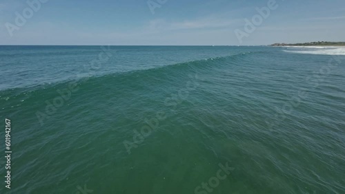 Wave crashing towards coastline of Costa Rica, aerial FPV follow view photo