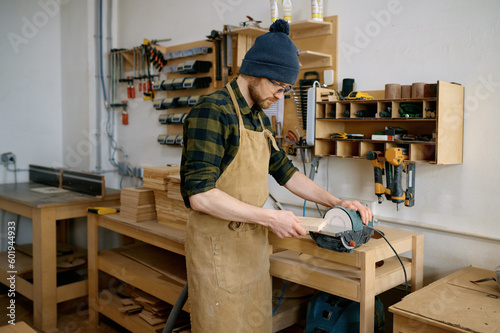 Woodworker using circular saw blade for cutting wood plank