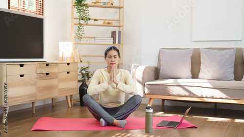 Sporty woman meditating to practice yoga exercise while doing yoga lotus position with namaste pose