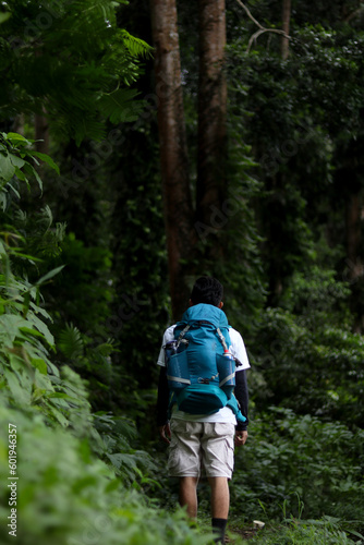 illustration of a hiker holding a blue backpack in the middle of a tropical rain forest © upen