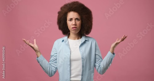 Emotional incomprehensible african american woman shrugging shoulders and raising hands asking Why standing over pink studio background photo