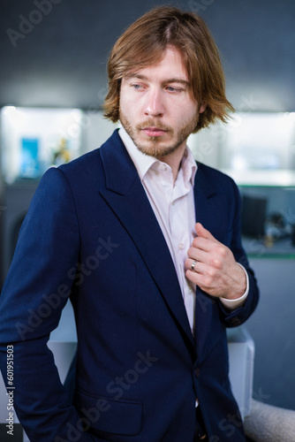 Portrait of a glamorous man in a stylish suit with a ring on his hand. A modern man with a beard poses for the camera in a jewelry store with diamonds.