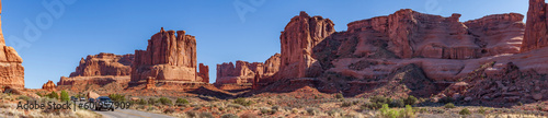 Cars with tourists drive along the road through Arches National Park admiring the diverse and unique forms of rocks, Utah, United States