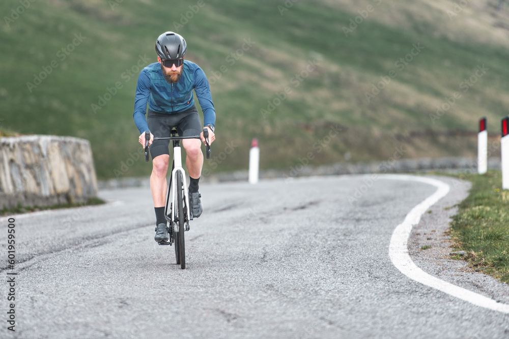Fototapeta premium Young man riding uphill on his bicycle