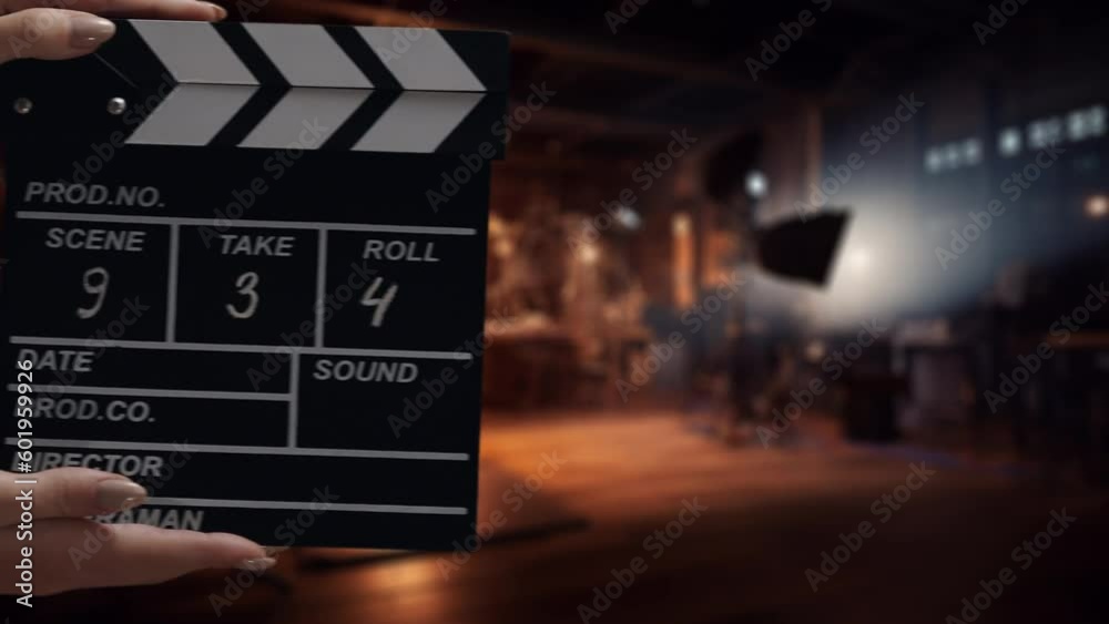 Human hands are using a clapperboard on set. Beginning of scene in film or TV television production. Concept of cinematography movie or video crew. Stage and filmmaking equipment background