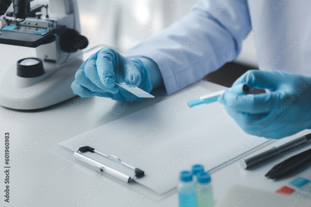 Lab assistant, medical scientist, chemistry researcher holds a glass tube through a chemical test tube, does a chemical experiment and examines a patient's sample. Medicine and research concept. Lab assistant, medical scientist, chemistry researcher holds a glass tube through a chemical test tube, does a chemical experiment and examines a patient's sample. Medicine and research concept.