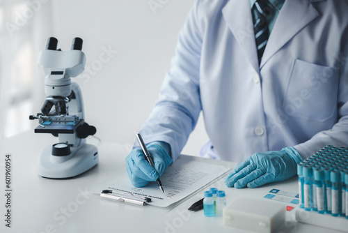 Lab assistant, medical scientist, chemistry researcher holds a glass tube through a chemical test tube, does a chemical experiment and examines a patient's sample. Medicine and research concept.