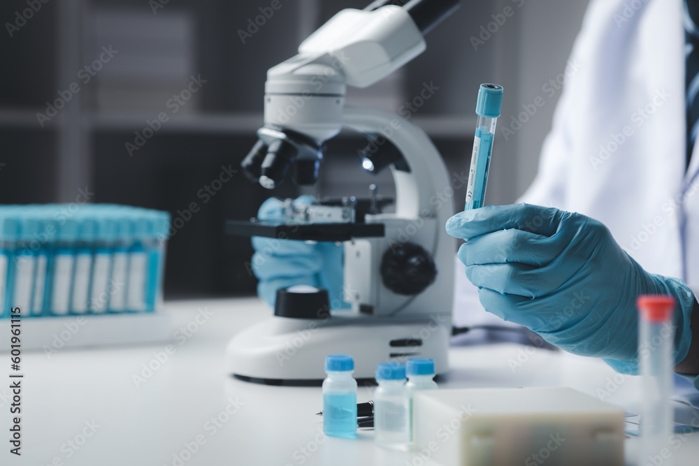Lab assistant, medical scientist, chemistry researcher holds a glass tube through a chemical test tube, does a chemical experiment and examines a patient's sample. Medicine and research concept. Lab assistant, medical scientist, chemistry researcher holds a glass tube through a chemical test tube, does a chemical experiment and examines a patient's sample. Medicine and research concept.