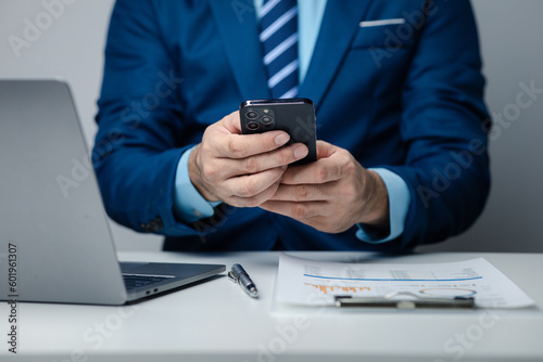 Business man looking at financial information from a mobile phone, he is checking company financial documents, he is an executive of a startup company. Concept of financial management.